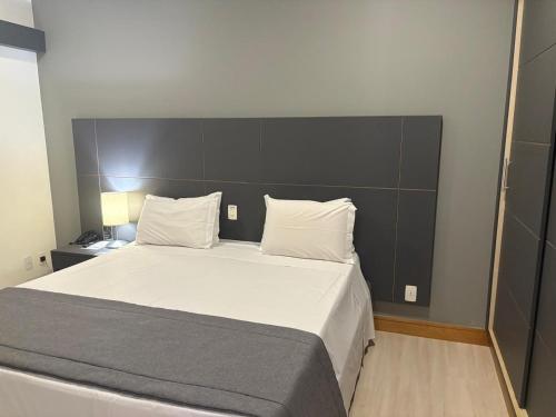 a bedroom with a large bed with white sheets and pillows at Araucária Flat Apto 305 in Ribeirão Preto