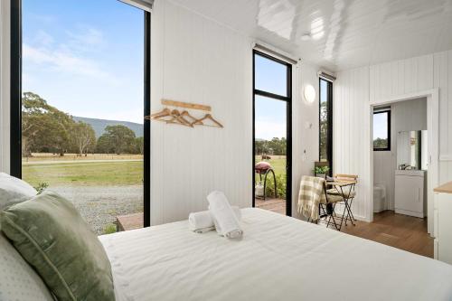 a bedroom with a large white bed and a large window at Halls Haven Tiny House 2 by Tiny Away in Halls Gap