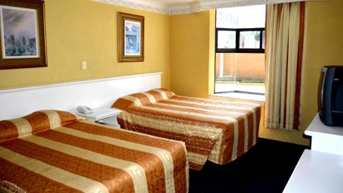 a hotel room with two beds and a television at Hotel San Jeronimo Inn in Toluca