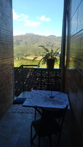 a table and a chair on a balcony with a view at Maxi conforto e vista para o Itacolomi in Ouro Preto