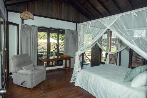 a bedroom with a bed and a chair and a desk at Bobocha Tangkoko Nature Resort in Bitung