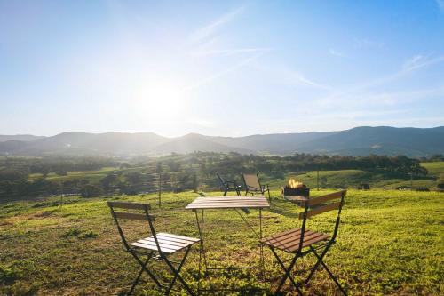 two chairs and a table in a field with a fire at Nichol Road Hideaway at Annies Retreat by Tiny Away in Yackandandah