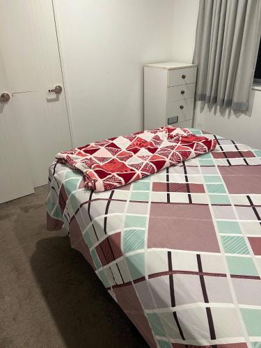 a bed with a quilt on it in a bedroom at 1 Spacious bedroom available in Auckland