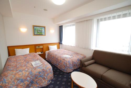 舞鶴市にあるホテルアルスタインのベッド2台とソファが備わるホテルルームです。
