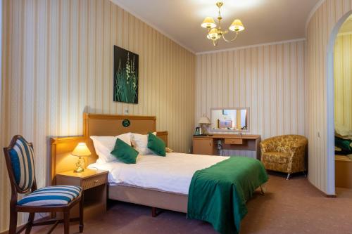 a bedroom with a bed and a desk and a chair at Elit Garden Hotel in Kamianets-Podilskyi