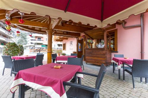 a restaurant with pink tables and chairs and a kitchen at Hotel Arisch in Aprica