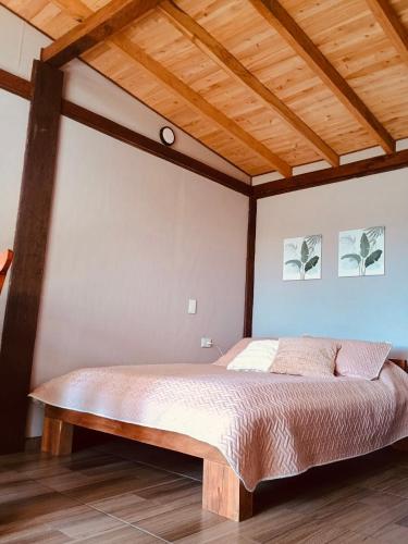 a bed in a room with a wooden ceiling at Quirama Lodge Oriente Antioqueño in Carmen de Viboral