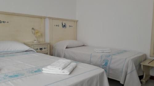 two beds in a room with towels on them at I Mandorli in Olbia