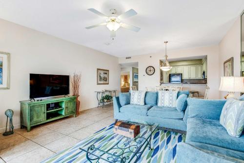 a living room with a blue couch and a tv at TOPS'L Summit 1013 in Destin