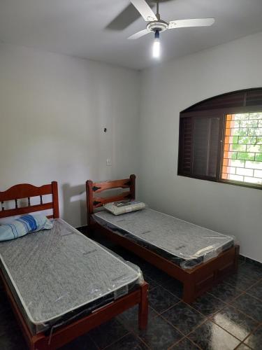 two beds in a room with a ceiling fan at Area de Lazer Rural in Ribeirão Preto