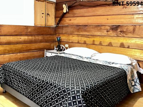 a bedroom with a bed with a wooden wall at Cabañas rurales Aldea de Cabal - Naturaleza y Sabor cerca a Termales Reservamos tu entrada a termales Santa Rosa in Santa Rosa de Cabal