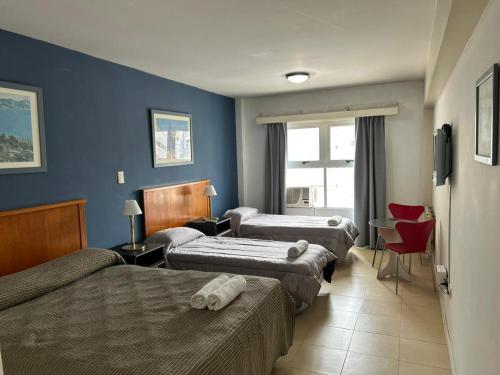 a hotel room with three beds and a window at Hotel Atlántico Suites in Mar del Plata