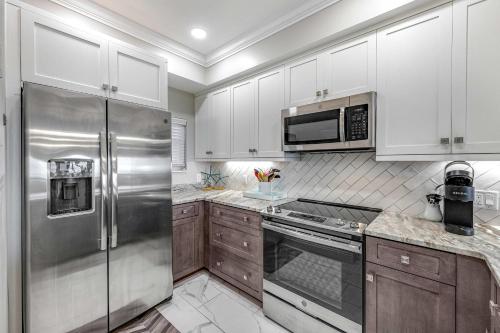 a kitchen with white cabinets and a stainless steel refrigerator at Condo with Shoreline Views and Resort Pools in Destin