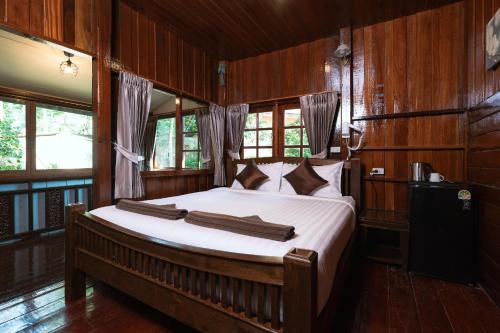 a bedroom with a bed with wooden walls and windows at Asia Divers Resort in Ko Tao