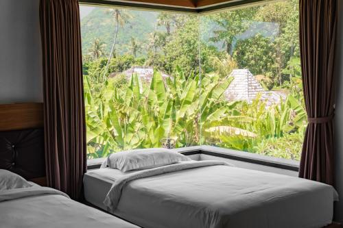 a bedroom with two beds and a large window at Gunung Agung Timur in Amed