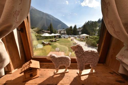 two sheep standing in a window looking at a view at Hotel La Rouja in Champoluc