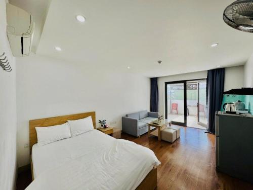 a bedroom with a white bed and a living room at Salux Hotel in Danang