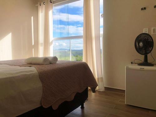 a bedroom with a bed and a window with a fan at Pousada Valley House in Piranhas