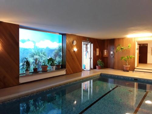 a swimming pool in a house with a large screen tv at Hotel Haselried in Tirolo