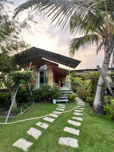 a house with a palm tree and stepping stones in the yard at Homestay GETA House in Ấp Thanh Sơn (1)