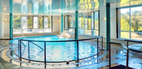 - une grande piscine dans une pièce dotée de fenêtres dans l'établissement Hotel Balneario Río Pambre, à Palas de Rei