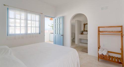 a white bedroom with a white bed and a blue door at Punta Mayia in Brisas de Zicatela