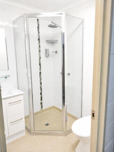 a shower with a glass door in a bathroom at Cedar Lodge Motel in Townsville