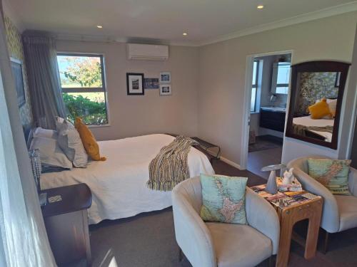 a bedroom with a bed and two chairs and a mirror at Ra-ata Farm in Rangiora