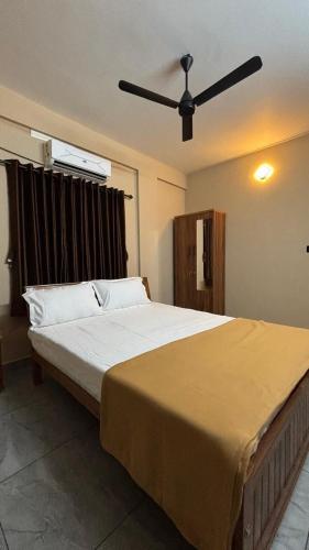 a bedroom with a large bed with a ceiling fan at New Castle Residency in Cochin