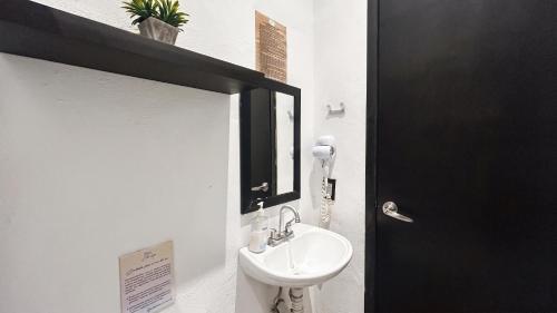 a bathroom with a white sink and a black door at Hotel y Beach Club Casa Mia Xulha -Bacalar in Xul-Ha