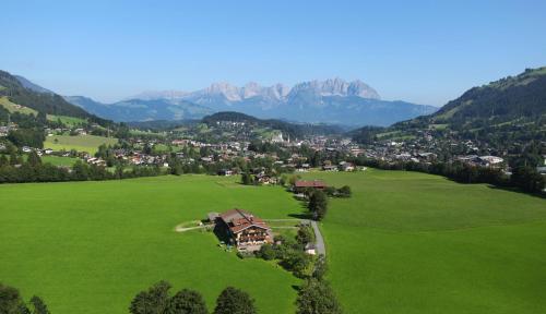 a house in a green field with mountains in the background at Lindenhof in Kitzbühel
