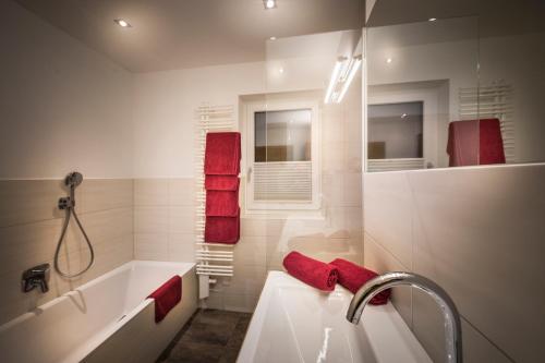 ein Badezimmer mit einer weißen Badewanne und roten Handtüchern in der Unterkunft Appartements Die Rifflerin in Going