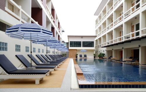 a pool with chairs and umbrellas in a building at Phangan Pearl Villa in Haad Rin