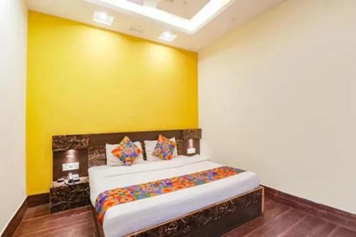 a bedroom with a large bed with a yellow wall at FabHotel Ambika Dx in Gwalior