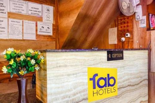 a table with a sign and a vase of flowers at FabHotel Ambika Dx in Gwalior