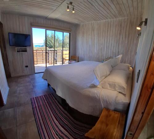 a bedroom with a large bed and a balcony at Cabañas Urmeneta Sur in Tongoy