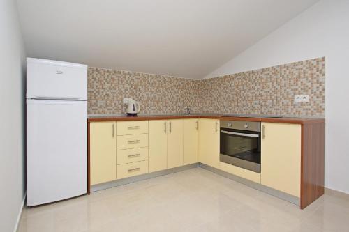a kitchen with a white refrigerator and cabinets at Apartmani Ruža in Novalja