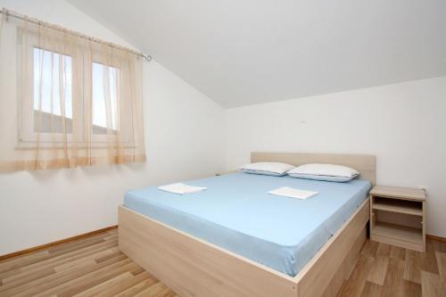 a white room with a bed and a window at Apartmani Ruža in Novalja