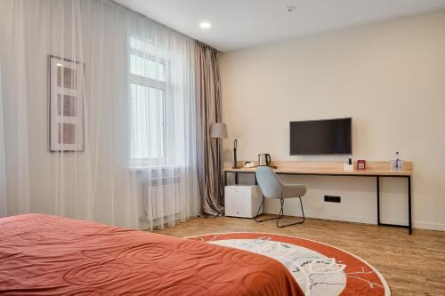 a bedroom with a bed and a desk with a television at Aisha Bibi Hotel & Spa in Astana