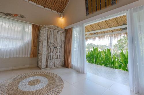 a room with a large window and a large rug at Coco Verde Bali Resort in Tanah Lot