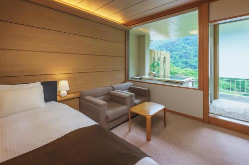 a bedroom with a bed and a chair and a window at Marumine Kanko Hotel in Aizuwakamatsu