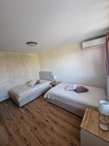 two beds in a room with wooden floors at Престиж in Arbanasi