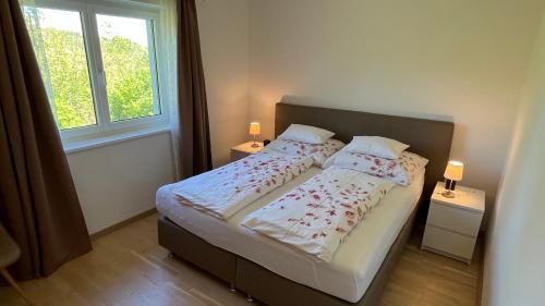 a bedroom with a bed with two night stands and a window at Wohlfühlapartments Steiner in Altmünster