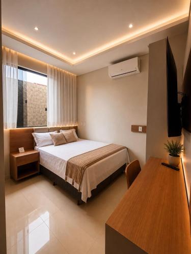 a bedroom with a bed and a television and a table at Hotel El Shaddai in Pontes e Lacerda