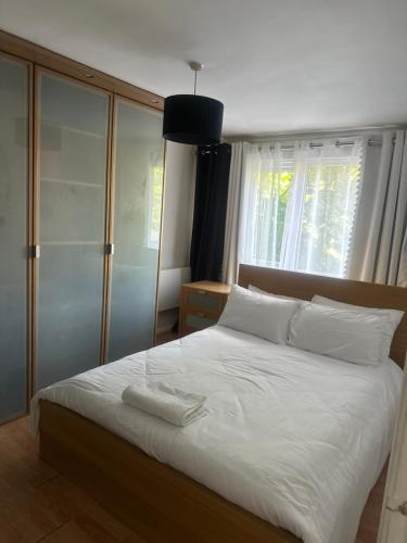 a bedroom with a large bed with white sheets and pillows at Charming Flat in North London in Edmonton