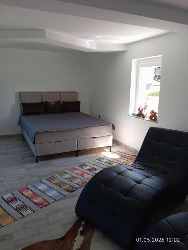 a bedroom with a bed and a couch and a window at WallerKarpfenBosnien in Šiljkovača