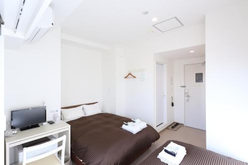 a bedroom with a bed and a tv on a desk at Oak Hotel Edo in Tokyo