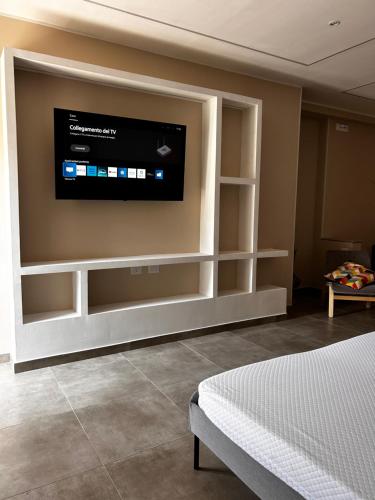 a bedroom with a flat screen tv on the wall at TownHouse Piraino B&B in Brolo