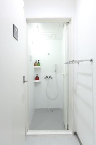 a white bathroom with a shower with a glass door at Oak Hotel Edo in Tokyo
