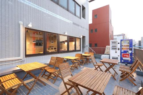 Oak Hotel Edo في طوكيو: مجموعة من الطاولات والكراسي الخشبية على الفناء